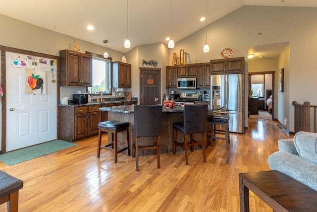 kitchen featuring stainless steel appliances, a center island, light wood-type flooring, and decorative light fixtures