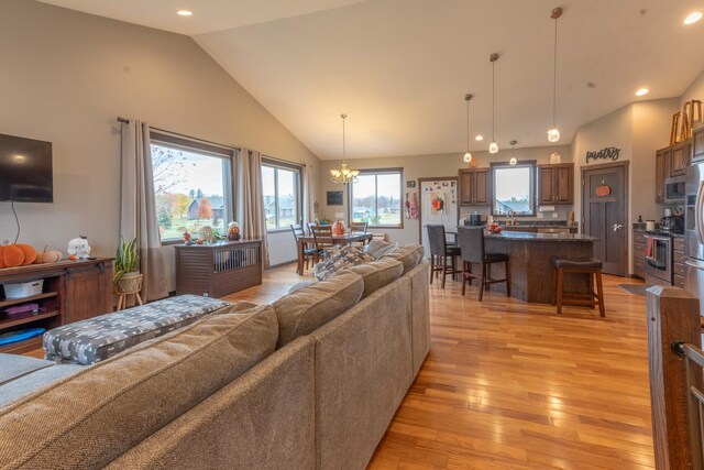 living room featuring an inviting chandelier, high vaulted ceiling, and light hardwood / wood-style floors