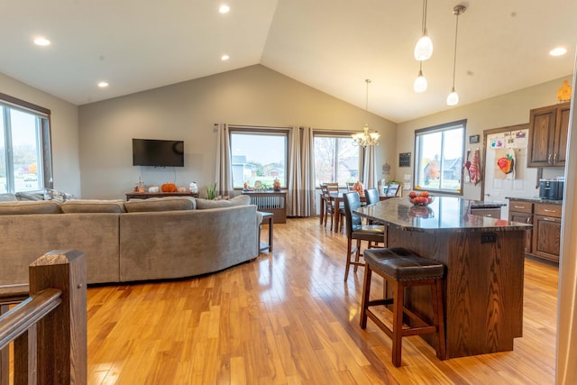 living room featuring light hardwood / wood-style floors, lofted ceiling, and an inviting chandelier