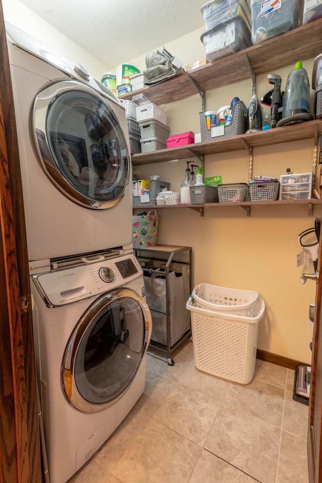 laundry area featuring stacked washer / dryer and light tile patterned flooring