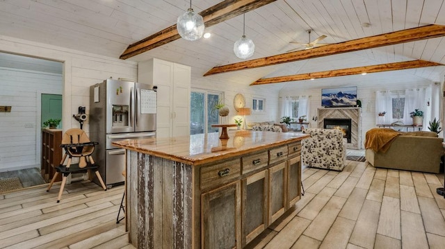 kitchen featuring stainless steel fridge, light wood-type flooring, vaulted ceiling with beams, decorative light fixtures, and a center island