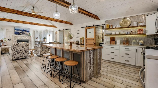 kitchen with white cabinetry, a kitchen bar, pendant lighting, and a barn door