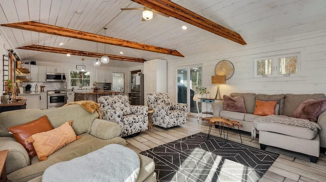 living room featuring beamed ceiling, wooden walls, light hardwood / wood-style floors, and ceiling fan