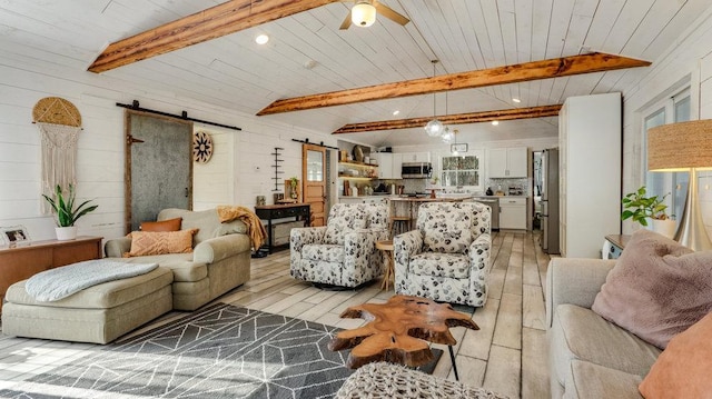 living room with beam ceiling, a barn door, and light wood-type flooring