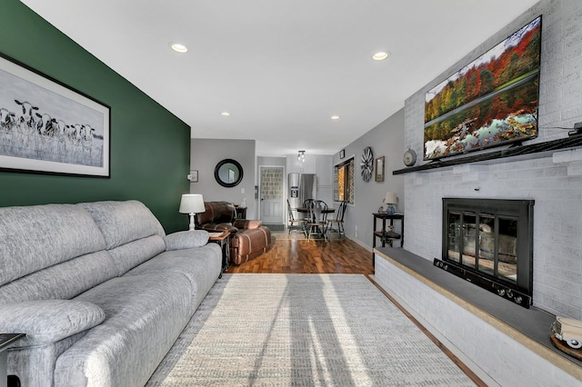 living room featuring wood-type flooring and a brick fireplace