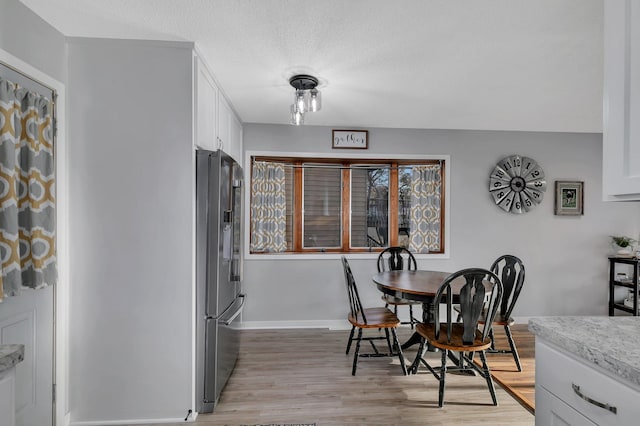 dining space featuring a textured ceiling and light wood-type flooring