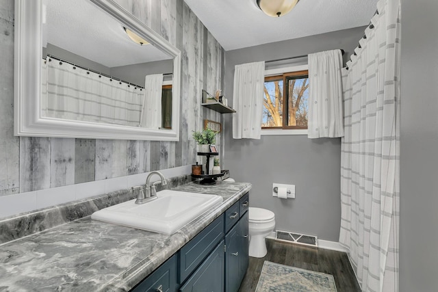 bathroom with toilet, vanity, a textured ceiling, and hardwood / wood-style flooring