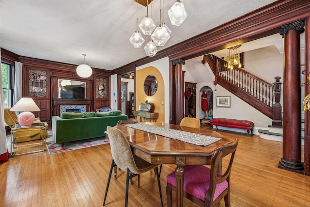 2742 Dupont Ave S, Minneapolis, MN 55408 - dining space featuring decorative columns, a chandelier, stairs, ornamental molding, and light wood-style flooring