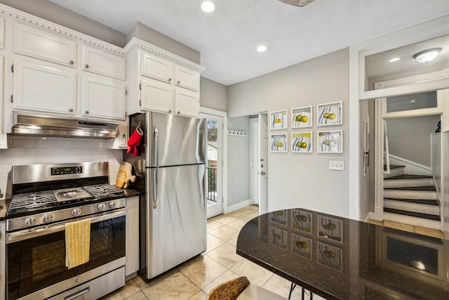 2742 Dupont Ave S, Minneapolis, MN 55408 - kitchen with stainless steel appliances, under cabinet range hood, white cabinets, backsplash, and light tile patterned floors