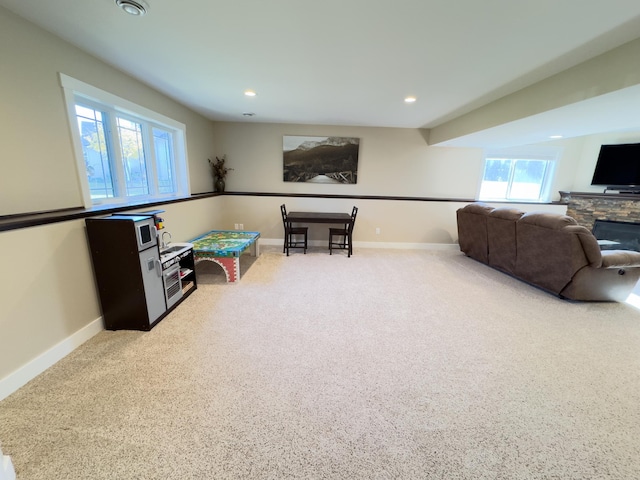 playroom featuring a stone fireplace, carpet, and a wealth of natural light