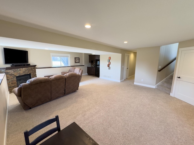 carpeted living room with a stone fireplace