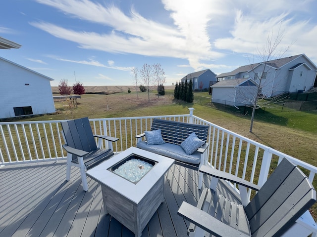 wooden terrace with a fire pit and a lawn