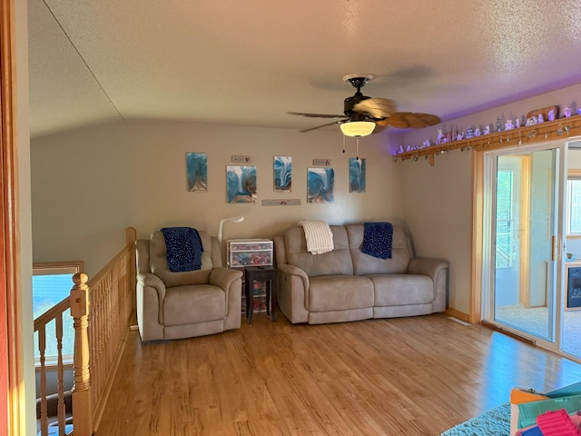 living room with lofted ceiling, a textured ceiling, light hardwood / wood-style floors, and ceiling fan