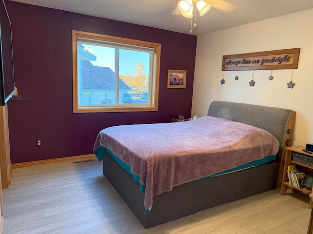 bedroom featuring light hardwood / wood-style floors, a textured ceiling, and ceiling fan