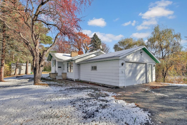 view of snowy exterior with an outbuilding and a garage