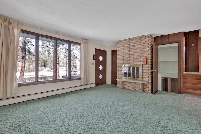 unfurnished living room featuring carpet floors, baseboard heating, wooden walls, and a brick fireplace