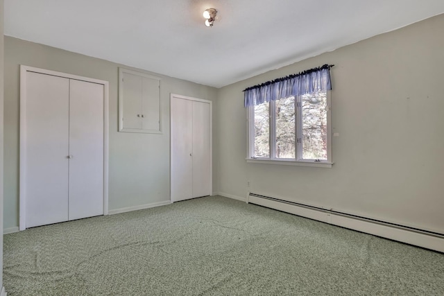 unfurnished bedroom featuring carpet, two closets, and a baseboard radiator