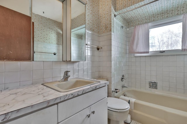 full bathroom with tasteful backsplash, tile walls, toilet, vanity, and tiled shower / bath combo