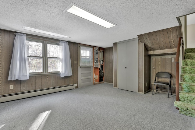 interior space featuring wooden walls, a textured ceiling, and baseboard heating