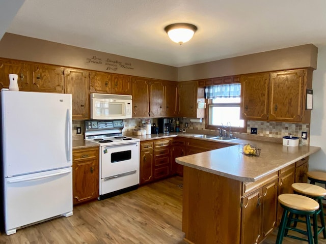 kitchen featuring white appliances, sink, kitchen peninsula, decorative backsplash, and light hardwood / wood-style flooring