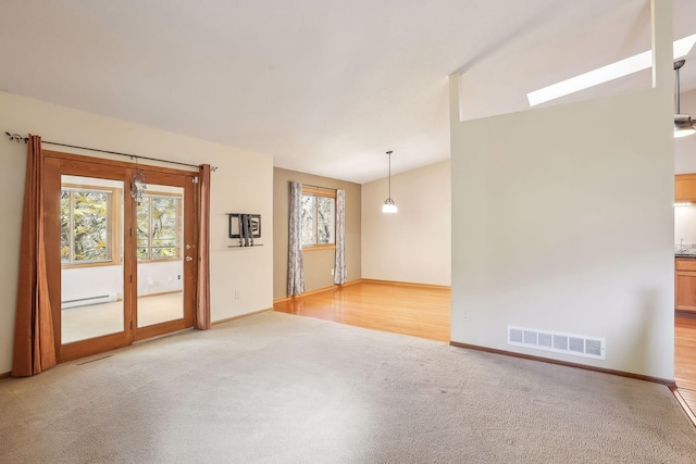 empty room featuring baseboard heating and hardwood / wood-style floors