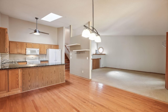 kitchen featuring white appliances, a skylight, kitchen peninsula, pendant lighting, and high vaulted ceiling