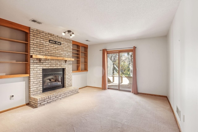 unfurnished living room featuring a brick fireplace, a textured ceiling, built in features, and light colored carpet