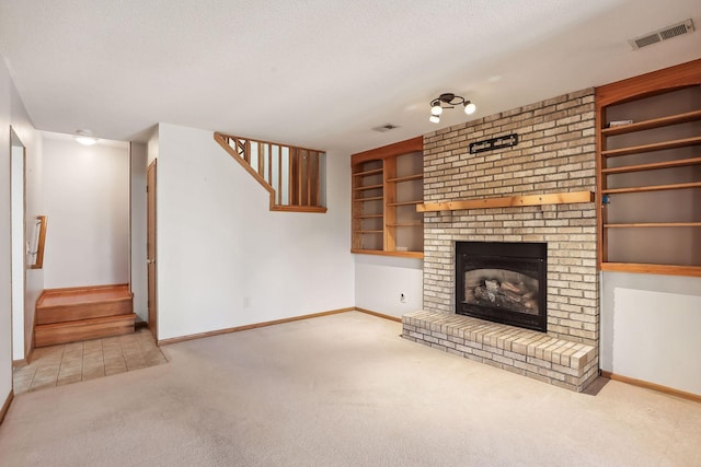 unfurnished living room featuring light carpet, a textured ceiling, built in features, and a brick fireplace