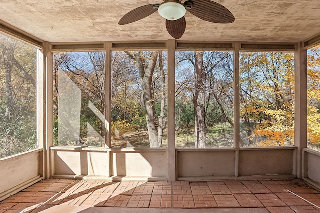 unfurnished sunroom featuring ceiling fan and a healthy amount of sunlight