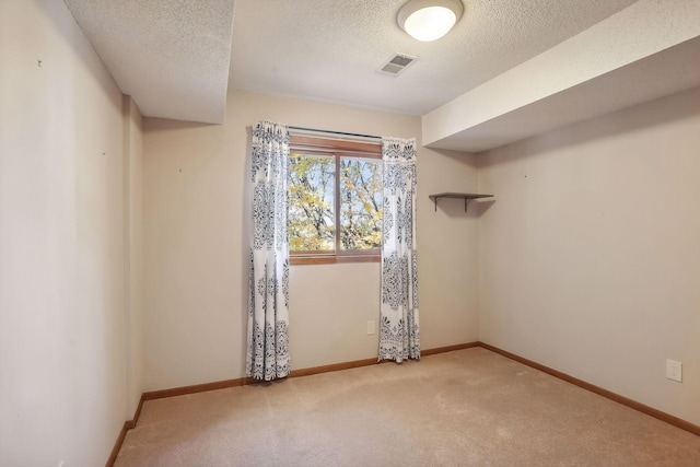 spare room featuring light carpet and a textured ceiling