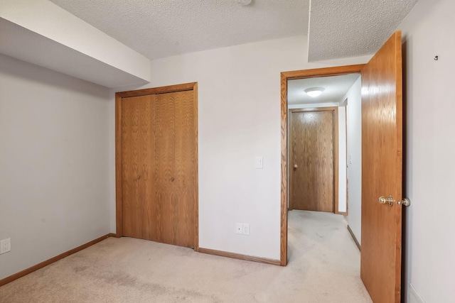 unfurnished bedroom with a textured ceiling, a closet, and light colored carpet