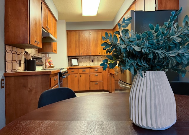 kitchen featuring backsplash, range with gas cooktop, and white fridge