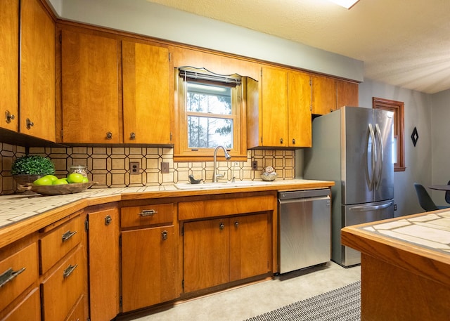 kitchen featuring tasteful backsplash, tile counters, sink, and stainless steel appliances