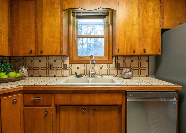 kitchen with backsplash, tile countertops, stainless steel dishwasher, and sink