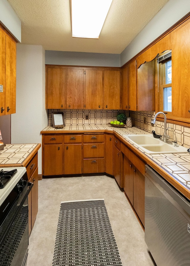 kitchen with gas stove, tile counters, sink, tasteful backsplash, and stainless steel dishwasher