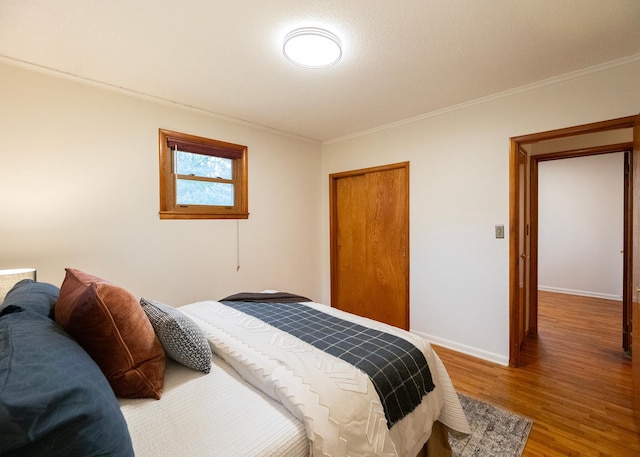 bedroom with hardwood / wood-style flooring, crown molding, and a closet