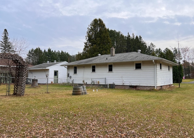 rear view of house featuring a lawn and central AC