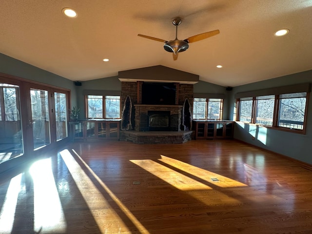 unfurnished living room featuring vaulted ceiling, ceiling fan, a fireplace, and dark hardwood / wood-style floors