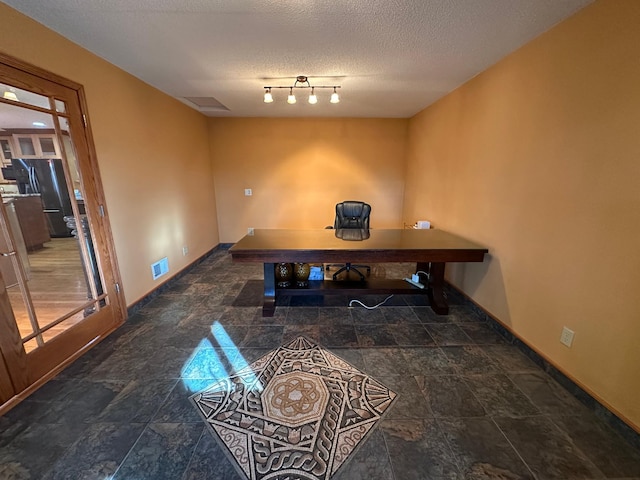 office space featuring track lighting and a textured ceiling