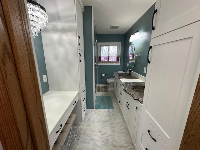 bathroom with a chandelier, vanity, and toilet