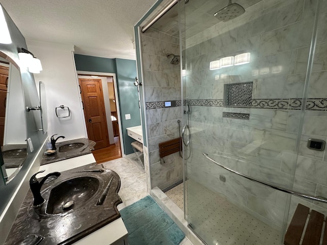 bathroom with a textured ceiling, vanity, and tiled shower