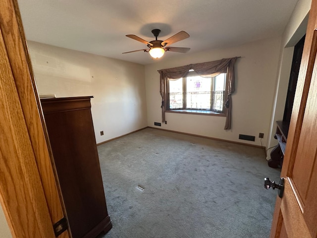 empty room with ceiling fan and light carpet