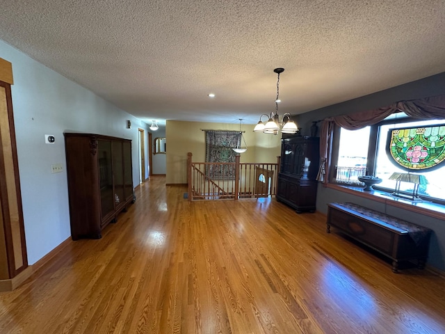 unfurnished dining area featuring a chandelier, wood-type flooring, and a textured ceiling