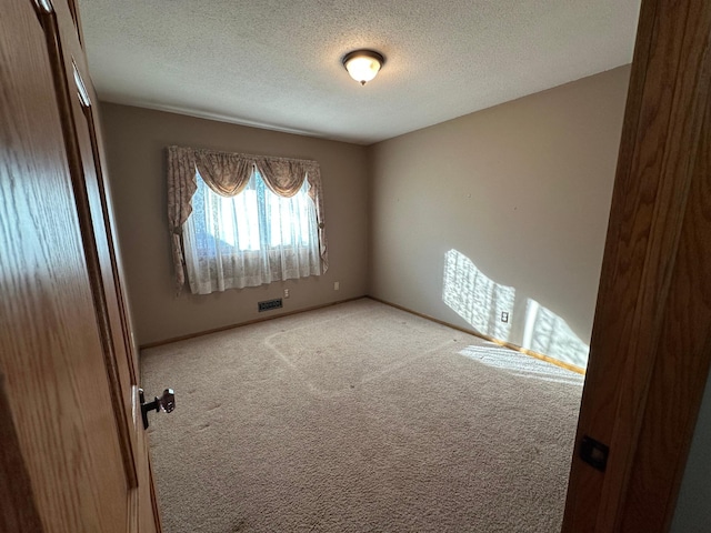 carpeted spare room featuring a textured ceiling