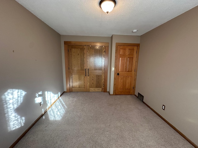 unfurnished bedroom with light carpet and a textured ceiling