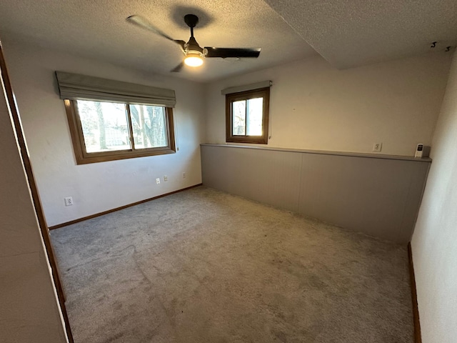 unfurnished room featuring light carpet, ceiling fan, and a textured ceiling