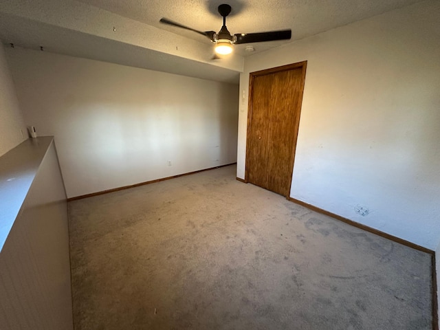 spare room featuring a textured ceiling, ceiling fan, and light carpet