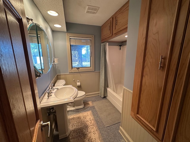 bathroom featuring shower / tub combo, a textured ceiling, and toilet