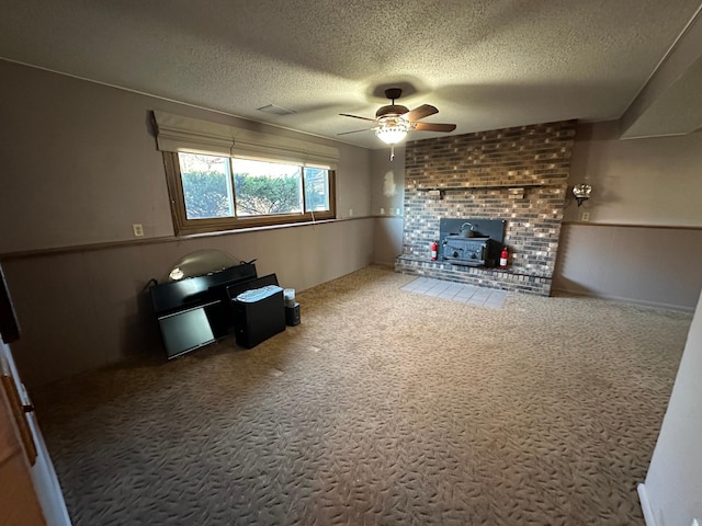 unfurnished living room with a wood stove, ceiling fan, carpet, and a textured ceiling