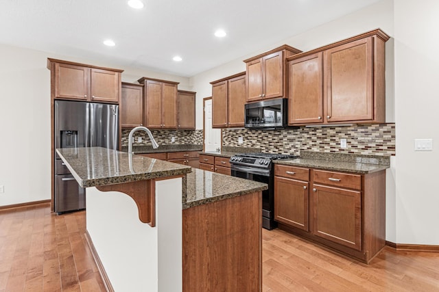 kitchen featuring a kitchen breakfast bar, light hardwood / wood-style flooring, stainless steel appliances, and an island with sink